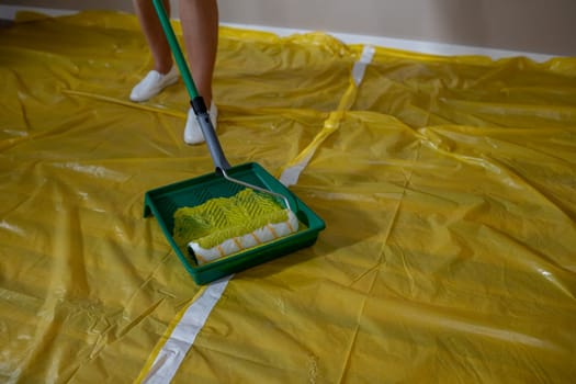 An individual is painting a large surface with a roller and tray, showcasing various home improvement activities