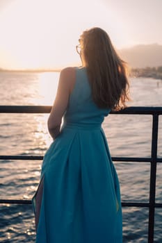 A woman in a flowing green dress poses on a pier by the sea at sunset, with a Turkey flag waving in the background.