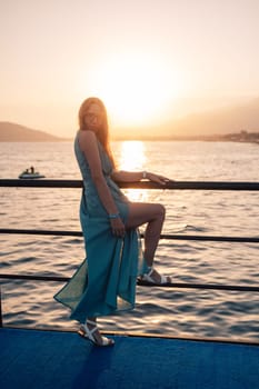 A woman in a flowing green dress poses on a pier by the sea at sunset, with a Turkey flag waving in the background.