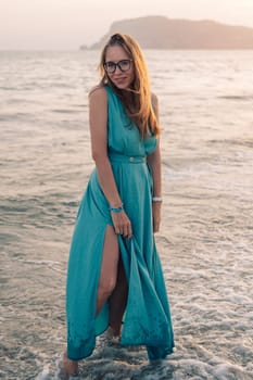 A woman in a flowing green dress poses on a pier by the sea at sunset, with a Turkey flag waving in the background.