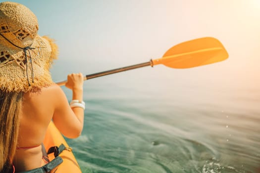 Woman in kayak back view. Happy woman with long hair in a swimsuit and hat floating in kayak on the sea. Summer holiday vacation. Summer holidays vacation at sea