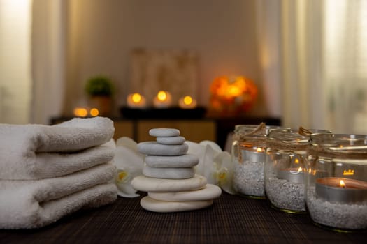 A serene spa environment features soft towels, stacked stones, and glowing candles, creating harmony