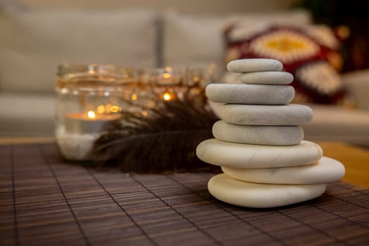 A beautifully serene arrangement of carefully stacked stones placed beside glowing candles and soft textures