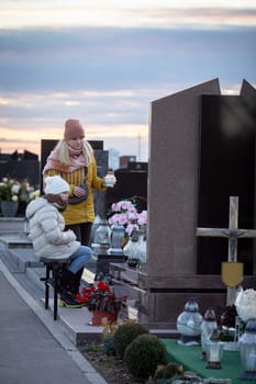 Family members gather at a serene cemetery during sunset to honor their beloved one in a poignant moment