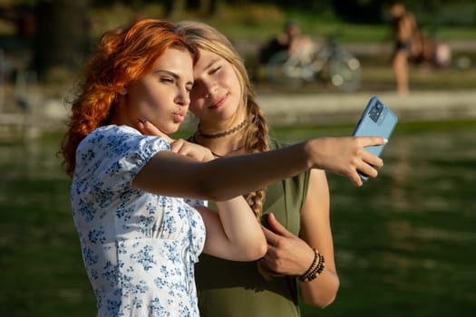 Two friends are having a fantastic time outdoors while taking a cheerful selfie by the glistening water