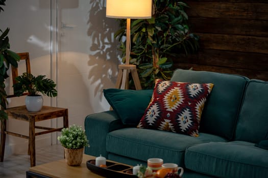 This stylish living room features a green sofa with pillows and plants, creating a vibrant atmosphere