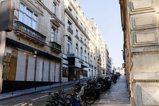 A narrow street in Paris with beautiful buildings and parked cars. Paris, France - November 24, 2024