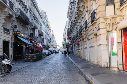 A narrow street in Paris with beautiful buildings and parked cars. Paris, France - November 24, 2024