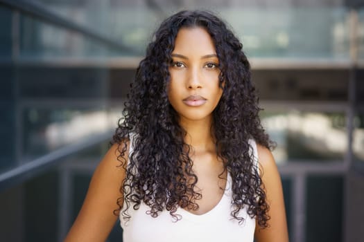 In an energetic urban setting, a confident young woman with beautiful curly hair stands out, exuding strength and grace, captivating viewers with her charming personality and magnetic presence
