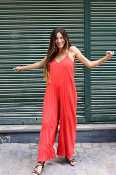 In a strikingly fashionable urban environment, a woman confidently poses wearing a vibrant red jumpsuit that radiates style and selfassurance, effortlessly capturing the essence of modern chic