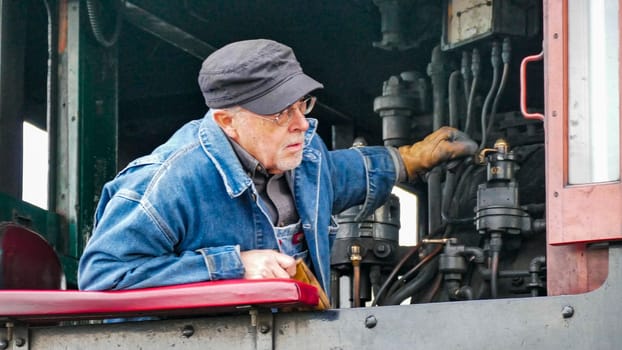 Strasburg, Pennsylvania, USA, December 31, 2024 - James Rice, A dedicated engineer adjusts the controls of a steam engine at a historic railway station, showcasing his expertise in maintaining vintage machinery on an autumn day.