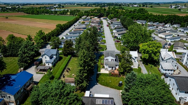 Residential Mobile, Manufactured, Prefab, Home Park with many houses and trees. The houses are white and the trees are green. The sky is cloudy and the houses are spread out