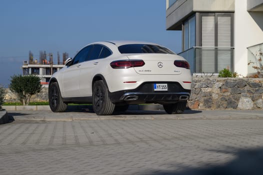 Gaziveren Cyprus -16.01.2025 A sleek white SUV sits gracefully on the cobblestone driveway of a contemporary structure under a clear blue sky.