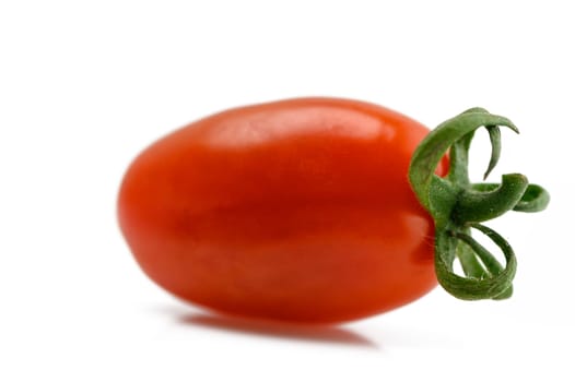 A bright red cherry tomato rests elegantly, emphasizing its shiny surface and fresh, juicy appeal.