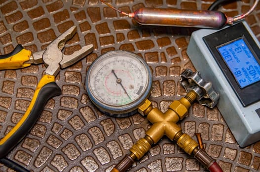 Tools for repairing refrigerators and air conditioners. Working hand tools. Service of air conditioners and refrigerators. Pliers, pressure gauge and multimeter. Working industrial equipment.