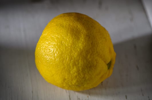 A vibrant lemon sits invitingly on a weathered wooden table, showcasing its fresh, zesty texture and color.