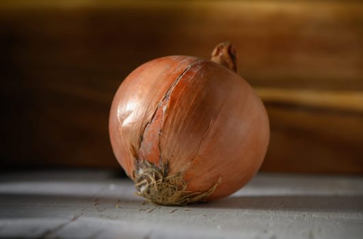 An orange onion sits on a rustic wooden table, softly lit, bringing warmth and charm to the kitchen environment.