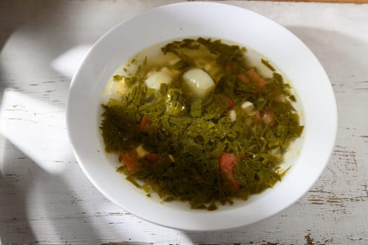 Nourishing green soup filled with vibrant vegetables and fresh herbs, served warm in natural daylight.