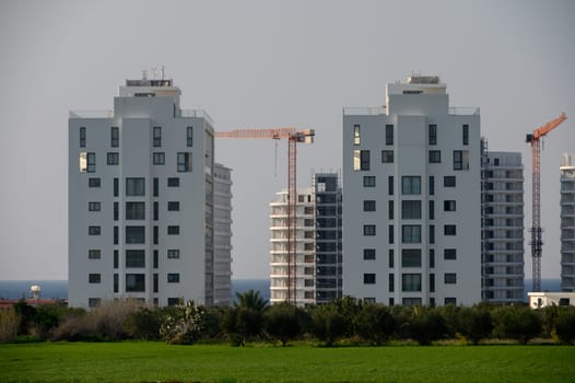 Twin towers rise above lush greenery, showcasing contemporary architecture while construction work continues nearby.