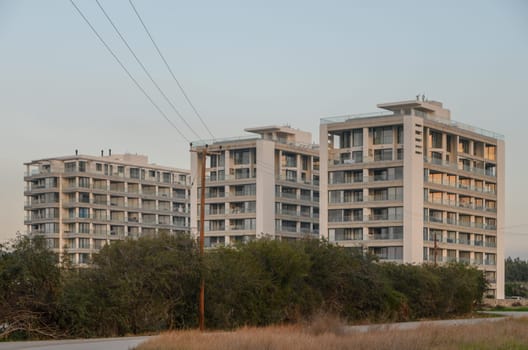 New high-rise apartments exhibit contemporary architecture, surrounded by greenery and bathed in soft evening light.