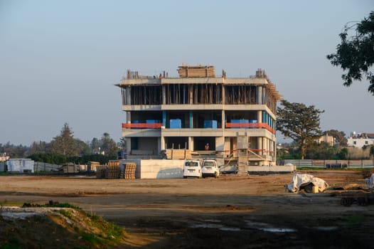 Workers continue to build a multi-story structure on a clear day as the project takes shape in the background.