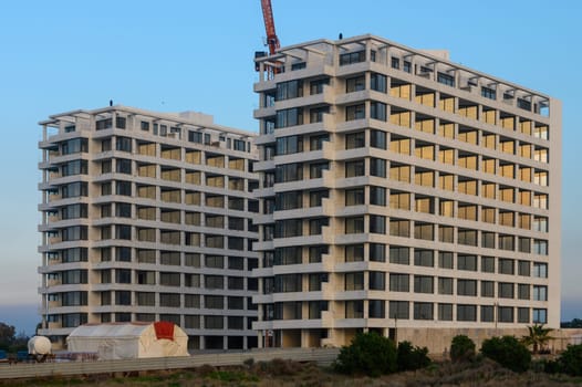 Two contemporary residential towers stand tall during twilight, showcasing architectural beauty beside the sea.