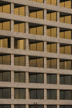 Golden hues reflect off large windows of a contemporary structure during twilight, showcasing modern design elements.