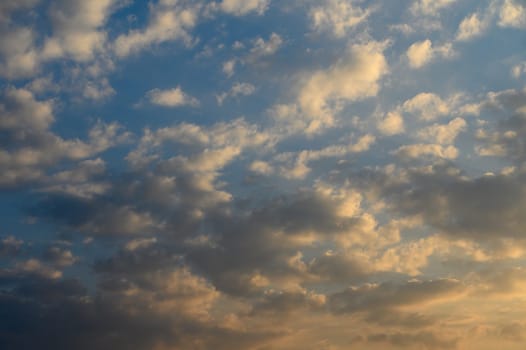 Colors blend as the sun sets, casting a warm glow on fluffy clouds drifting peacefully above the horizon.