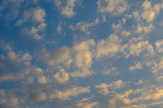 Fluffy clouds drift slowly across a vibrant blue sky, creating a peaceful atmosphere at dusk.