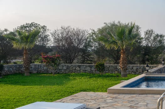 Tranquil outdoor space features a shimmering pool and vibrant garden, perfect for relaxation on a sunny day.