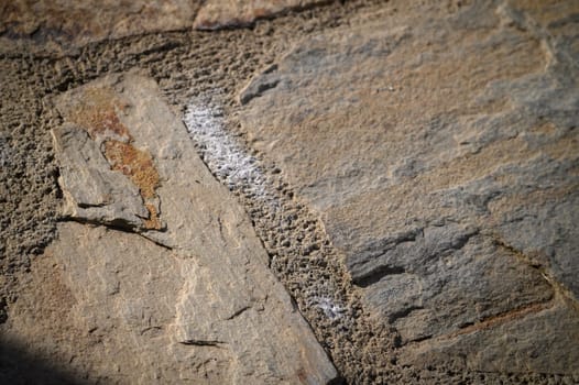 Sunlight highlights the intricate patterns and earthy tones of a rugged stone surface, creating a serene atmosphere.