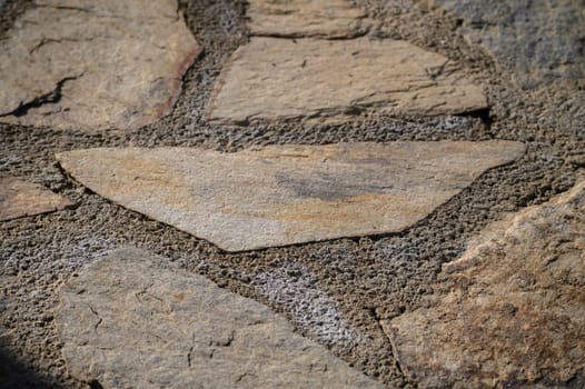 Warm sunlight reveals intricate textures and patterns of a well-worn stone path, inviting exploration and tranquility.