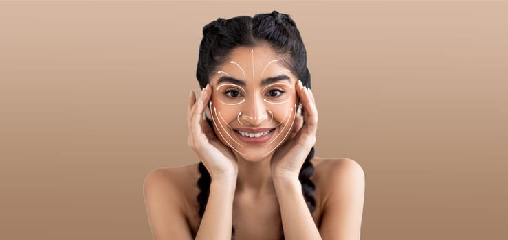 Indian woman enjoys her skin care routine, smiling and engaging in a pampering activity. She holds her face, highlighting her beauty regime in an isolated setting with soft, neutral tones.