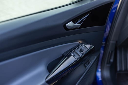 Window control buttons in modern luxury electric car. Car leather interior details of door handle with windows controls and adjustments. Car window controls. Door handle with power window control.
