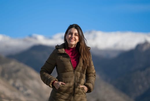 Portrait of a smiling woman enjoying a sunny winter day in a mountain landscape