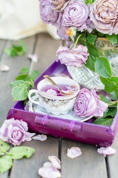 still life with a bouquet of half-withered ash-lilac Novalis roses, with a cup of refreshing cold tea on a summer day,view from an angle
