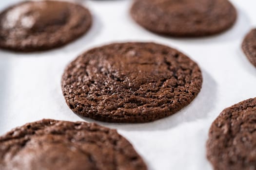 Cooling freshly baked chocolate cookies with chocolate hearts for Valentine's Day on a kitchen counter.