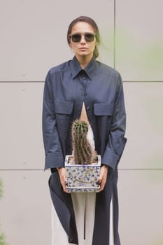 Woman tenderly standing in kimono with cactus in her hands on gray background. The girl seductively wear her robe. Fashionable details of kimono on grey background