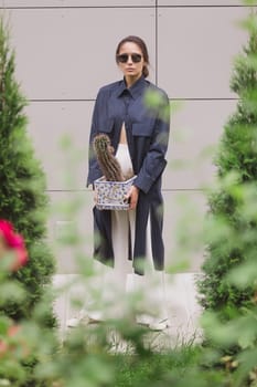 Woman tenderly standing in kimono with cactus in her hands on gray background. The girl seductively wear her robe. Fashionable details of kimono on grey background