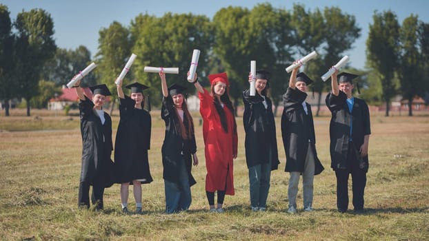 Young graduates pose and wave diplomas in their hands in the street