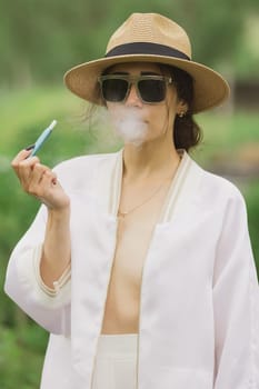 beautiful woman smoking electronic cigarette in street.