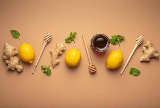 Composition with lemons, mint, ginger, honey in glass jar and honey wooden dippers top view. Food for immunity stimulation and against seasonal flu. Healthy natural remedies to boost immune system.