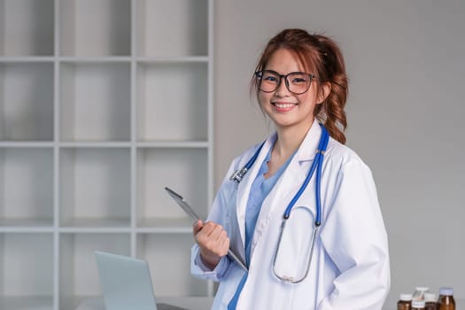 Portrait of a smiling female doctor holding a digital tablet wearing a medical coat and stethoscope in hospital.