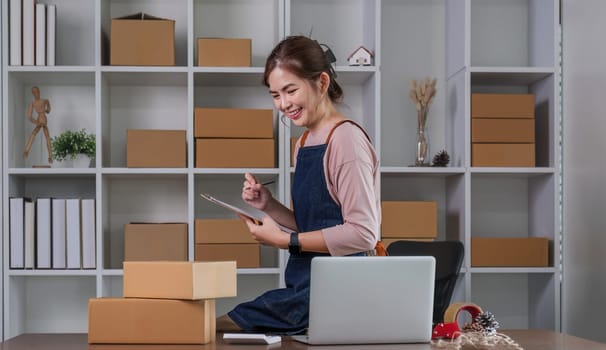 Startup small business entrepreneur SME, asian woman packing cloth in box. Portrait young Asian small business owner home office, online sell marketing delivery, SME e-commerce telemarketing concept.