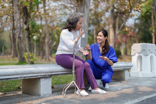 Patient care, female care, young Asian women are taking care of the elderly, providing crutches and walking for patients, and exercising their legs and knees in the park parks