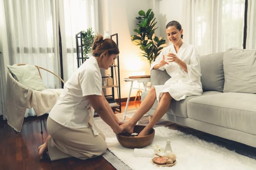 Woman indulges in blissful foot massage at luxurious spa salon while masseur give reflexology therapy in gentle day light ambiance resort or hotel foot spa. Quiescent