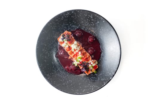 Salmon tataki in in cherry sauce on a black plate isolated. High quality photo