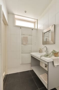 a modern bathroom with black tile flooring and white tiles on the walls, there is a large mirror above the sink