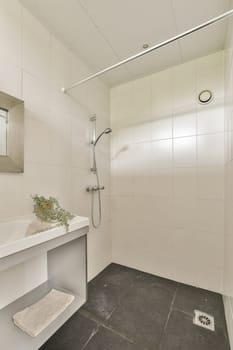 a bathroom with a sink, mirror and shower head mounted on the wall next to it is a flower in a vase
