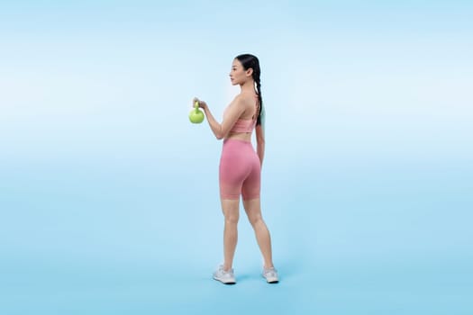 Vigorous energetic woman doing kettlebell weight lifting exercise on isolated background. Young athletic asian woman strength and endurance training session as body workout routine.